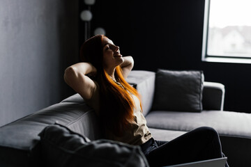 Naklejka premium Young relaxed woman resting while sitting with laptop on sofa at living room