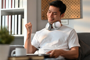 Excited man looking at digital tablet screen and celebrating success, received good news in message, showing yes gesture