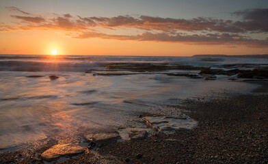Dramatic beautiful sunset on a rocky coast. Bright sun light on the horizon
