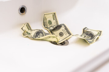 Money is thrown away in the sink. This photo concept illustrates the financial condition of a business that is failing or going bankrupt so that it only wastes money without results