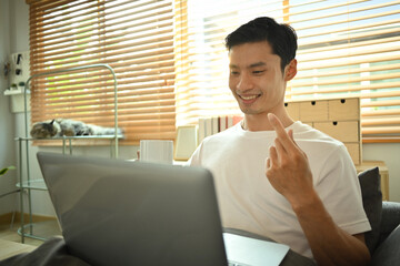 Smiling asian man making video call on laptop, talking and gesturing while explaining something. Technology and communication