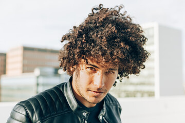 Urban style portrait of a handsome North African boy with a captivating gaze while looking into the camera dressed in a leather jacket