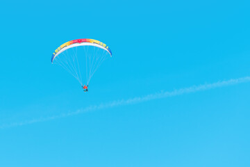 Unrecognizable paraglider flying across the sky with paragliding instructor