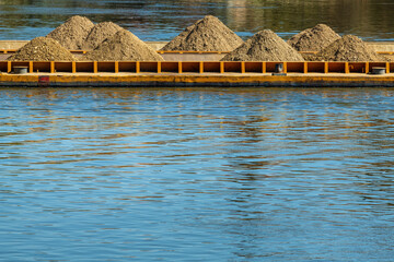 A barge, flat-bottomed boat, pushed by tugboat along the river to transport gravel and grit