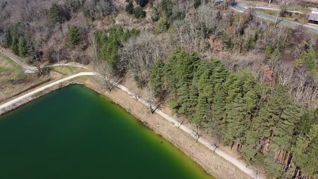 Groupe de sportifs courant sur un grand chemin blanc en castine le long d'un lac de couleur verte. Chemin castin&eacute; avec coureurs le long d'un grand lac de vives couleurs.