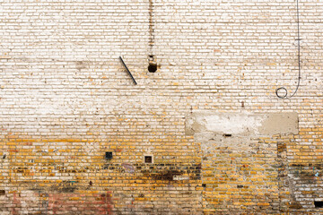 Old brick wall facade texture with white paint peeling off the surface as background