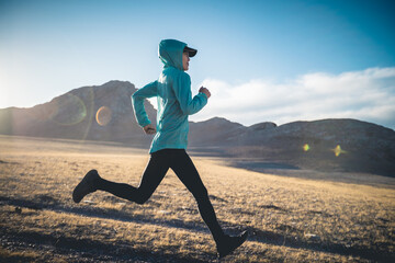 Woman trail runner cross country running in lakeside mountains
