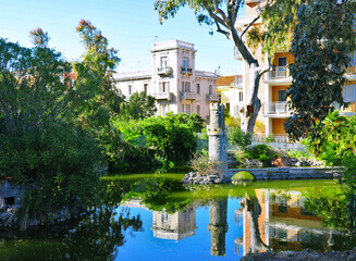 Fototapeta na wymiar Villa comunale con palazzo liberty che si rispecchia nel lago con la fontana artistica