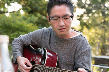 新緑の季節に屋外でギターを弾く男性
