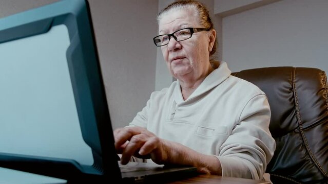 Mature woman with credit card, typing on a notebook keyboard, purchasing online. Victim of a online fraught, inputting credit card information.
