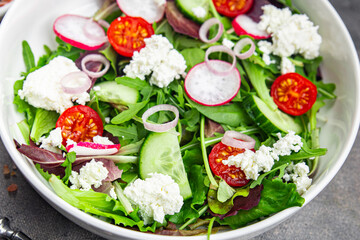 green salad cheese and vegetable radish, tomato, cucumber, green lettuce mix healthy meal food snack on the table copy space food background rustic top view keto or paleo diet veggie vegetarian food