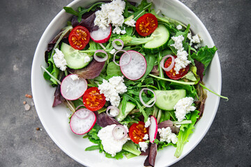 green salad cheese and vegetable radish, tomato, cucumber, green lettuce mix healthy meal food snack on the table copy space food background rustic top view keto or paleo diet veggie vegetarian food