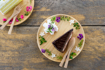 Slice of chocolate fudge cake and Coconut butter cream cake. Tasty homemade soft and delicious chiffon cake on table wooden plate. Top view of bakery and dessert.
