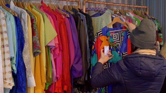 A customer is looking at colorful dresses in an antique store