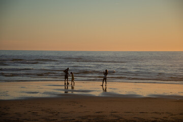 Fototapeta na wymiar des silhouettes à contre-jour au coucher de soleil sur la plage