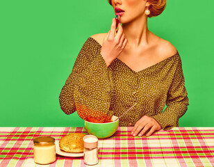 Oops. Cropped image of girl applying lipstick, having dinner, putting sleeve intovegetabel soup against green studio background. Food pop art photography. Concept of retro style, creative vision