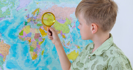 Boy is playing in travelers and seeking country on the map