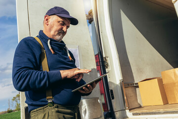 Fototapeta na wymiar Truck driver checking shipment list on a digital tablet while standing in back side cargo van vehicle.