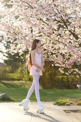 portrait of girl on roller skates in spring  park. Blooming trees