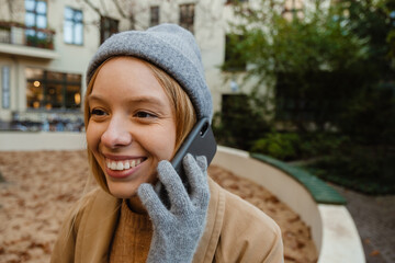 Cheerful woman talking on cellphone while sitting in yard