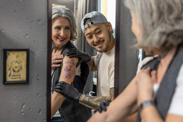 Long-haired woman looking in the mirror at her new tattoo