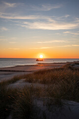 Sunset photo on a dune with the beach and a ship on the North Sea coast in Zeeland, Netherlands