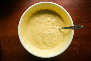 the process of making dough in a yellow toe with a spoon on a dark wooden table.