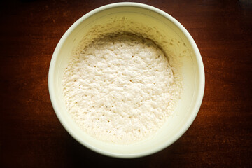 the process of cooking cooking dough in a yellow toe on a dark wooden table.