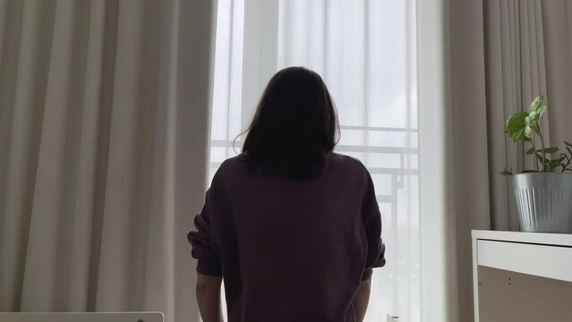 A young woman suffers from mental abuse at home. Gaslighting. Stressed, crying, covering his face with his hands in the bedroom.