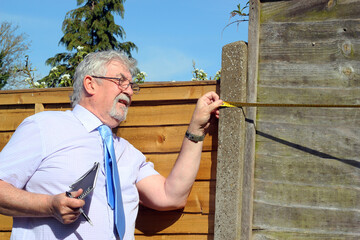 Real estate man measuring property with a tape measure. 