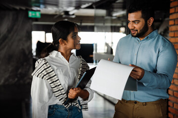 Indian business people examining documents while standing in office building