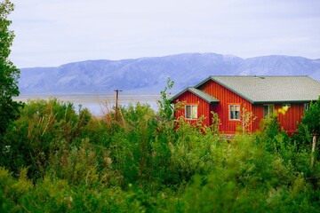 Scenic view of red wooden house on the shore of Mammoth lake against mountain, CA, USA