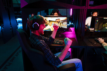 Excited man celebrating victory while playing online video game in cybersport club