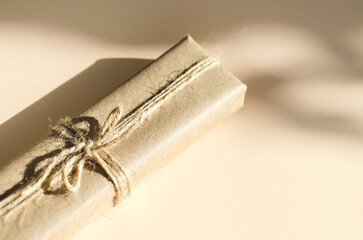 gift box in kraft paper and tied with twine on beige background. Vintage box made of brown eco-paper