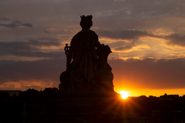 view on sunset behind la Ville de Paris statue on Pont du Carrousel in Paris