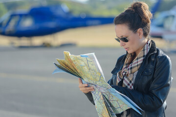 young woman helicopter pilot studying map before flight