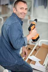 happy man putting together self assembly furniture in new home