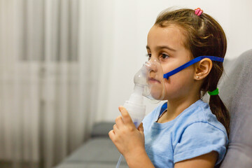 Little girl use inhaler nebulizer. Child asthma inhaler, nebulizer steam, flu or cold concept. Copyspace