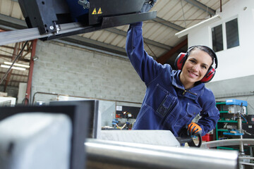 Fototapeta na wymiar smiling woman using factory machinery