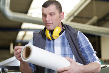 workman feeling texture of material on a roll