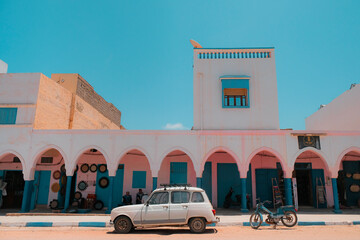 Mirleft, Morocco - colorful market exterior with blue doors and windows, pink walls, white arches....