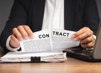 Businessman in a suit tearing up a contract while sitting at the table - obrazy, fototapety, plakaty