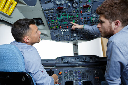 two men in aircraft cockpit apprentice asking a question