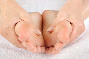 Young healthy woman massages her soles at relaxation, wellness or spa