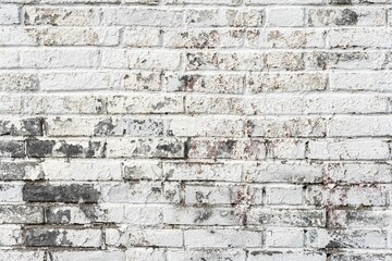 Plain brick wall background with spots of gray in the worn white paint
