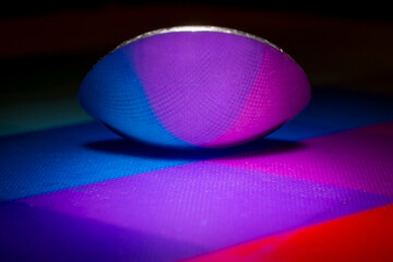 Abstract shot of a teaspoon reflecting colourful harlequin pattern. Graphic resource.