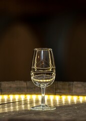Vertical shot of an empty wine glass on the yellow illuminated table