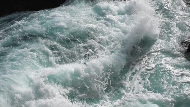 Pure bright turquoise waves break into white foam on the coastal cliffs and seethe between them. The need to protect the environment. Ecology and global warming. Slow motion.