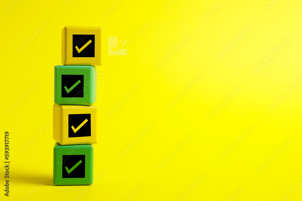 Wall mural Stacked cubes with check marks on yellow background. Space for text