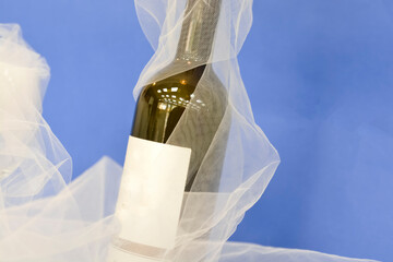 wine  bottle on blue background with a tulle
on it